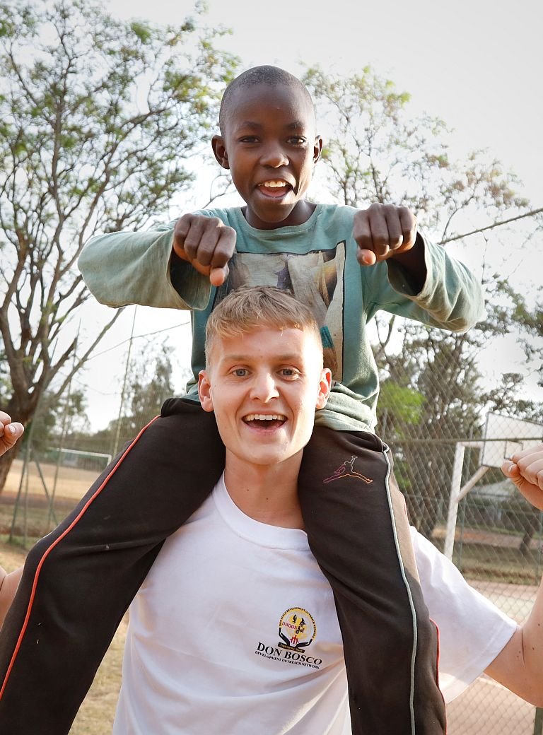 Luke Kelly trägt Jungen auf der Schuler im Bosco Boys Home in Nairobi