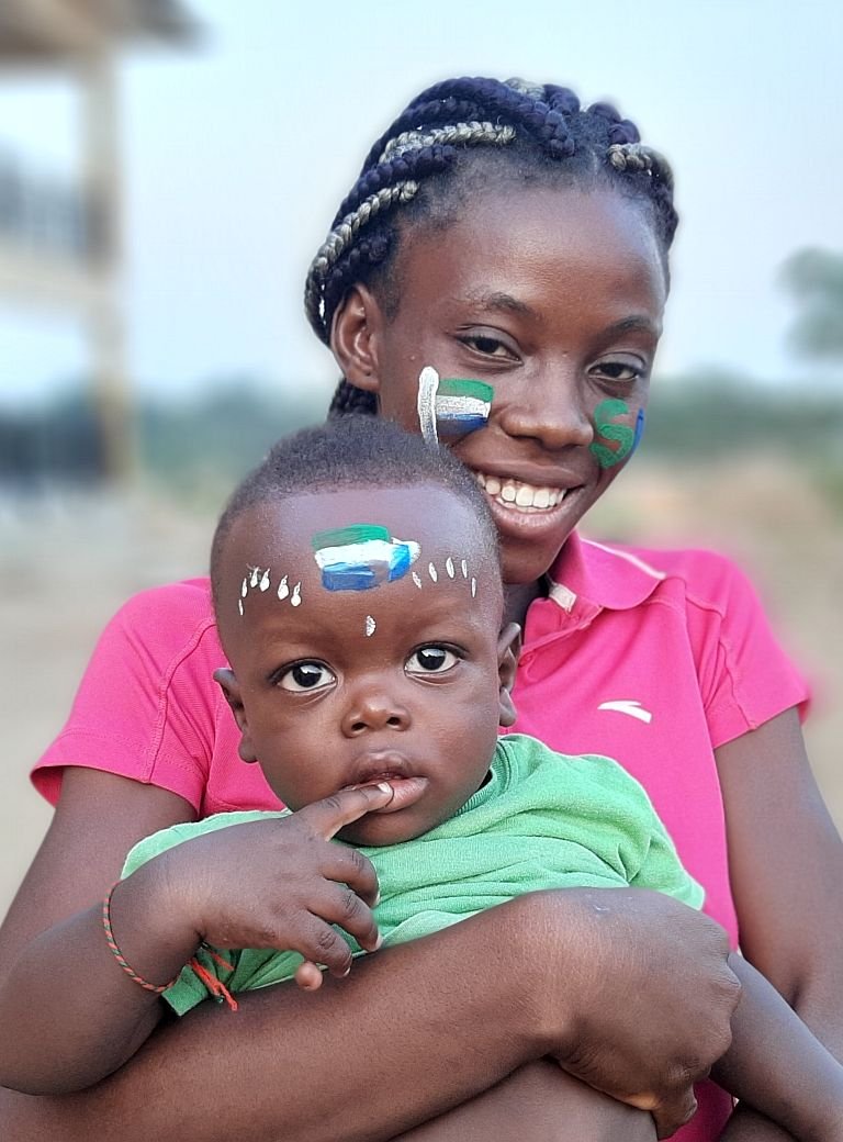 Junge Frau lächelnd mit Kleinkind auf dem Arm 