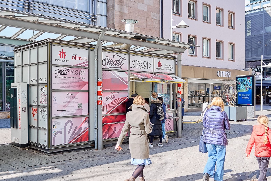 Smart Kiosk in der Nürnberger Fußgängerzone mit Besuchern und Passantinnen