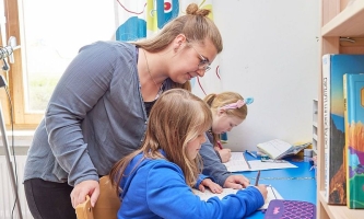 Kinder und Betreuerin bei Hausaufgaben bei Don Bosco 